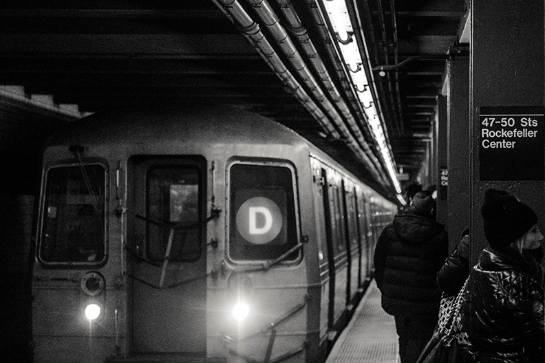 Grayscale picture of upcoming train at 50th Street Rockerfeller Center